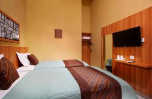 ein Hotelzimmer mit einem Bett und einem Flachbildfernseher in der Unterkunft Family & Superior Hotel Malioboro-Yogyakarta in Sentool + 9 Fotos