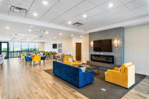 Un vestíbulo con sillas y mesas amarillas y una chimenea. en Comfort Inn & Suites, en Bradford