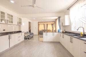 a kitchen with white cabinets and a living room at Jamii Villas Diani in Kwale