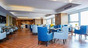 a restaurant with blue chairs and tables in a room at Echarm Hotel Xiantao Yuantai Weilaicheng in Xiantao
