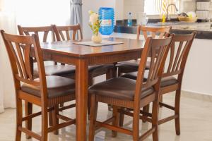 a dining room table with six chairs and a kitchen at Jamii Villas Diani in Kwale