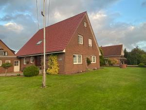 ein Haus mit rotem Dach auf einem grünen Rasen in der Unterkunft Haus Hanni Ferienwohnung Hanni in Hage Ostfriesland direkt am Kiessee und Kurpark - Nordseenah in Berumbur