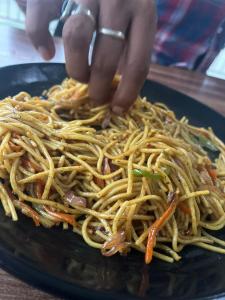a person reaching for a pile of noodles on a plate at River Side Gorilla Resort Mussoorie in Mussoorie