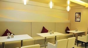 a dining room with white tables and white chairs at Jinjiang Inn Jinzhou Yunfei Bridge in Jinzhou