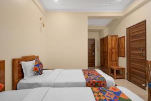 a bedroom with two beds and a wooden cabinet at FabHotel Marine - Vishnu Temple Bada Lalpur in Varanasi