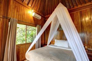 a bed in a wooden room with a mosquito net at Bali Rahayu Homestay in Munduk