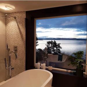 ein Bad mit einer Badewanne und ein großes Fenster mit Aussicht in der Unterkunft Lovely sea view in modern family house! in Steinkjer + 77 Fotos
