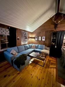 un salon avec un canapé bleu et une table dans l'établissement Utibakken - cabin ski inn-out Norefjell, à Surteberg