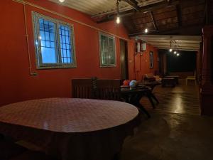 a room with orange walls and a table and chairs at Dark Sky Homestay in Mudigere