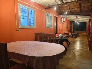 a room with orange walls and a table and chairs at Dark Sky Homestay in Mudigere