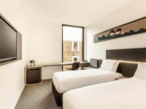 a hotel room with two beds and a flat screen tv at ibis Adelaide in Adelaide +50 photos