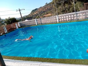 a person swimming in a swimming pool at Alojamiento Rural Manantial de los Cañitos in El Bosque