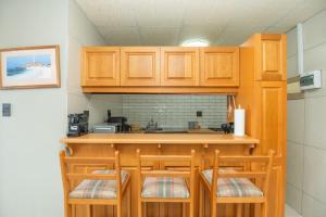een keuken met houten kasten en een bar met stoelen bij Cyprus Seas in Gqeberha