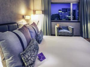 a large bed in a hotel room with a window at Mercure Santiago Centro in Santiago