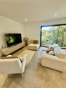 a living room with two couches and a flat screen tv at 2 villas mitoyennes in Monticello