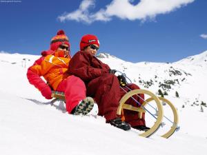 two people sitting on a sled in the snow at Chalet in Neukirchen by Wildkogel Ski Slopes in Neukirchen am Großvenediger