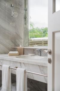 een badkamer met een wastafel, een spiegel en handdoeken bij METT Singapore in Singapore