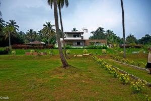 una casa en un campo con una palmera en Pollachi Riverhouse, A CGH Earth Saha experience, en Pollachi