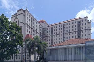 ein großes weißes Gebäude mit Bäumen davor in der Unterkunft 2BR Apartment Majesty W Pool in Bandung