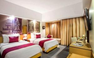 a hotel room with two beds and a desk at Hotel Radhe in New Delhi