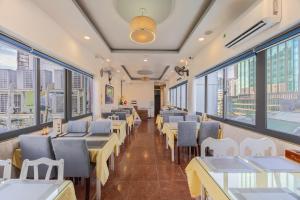 a restaurant with tables and chairs and windows at A25 Hotel - 35 Mạc Thị Bưởi in Ho Chi Minh City