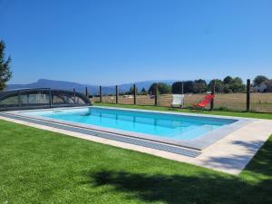 ein Swimmingpool in einem Hof mit grünem Gras in der Unterkunft Le petit cocon d'auré in Corbelin
