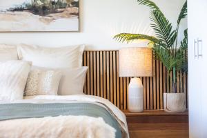 ein Schlafzimmer mit einem Bett, einer Pflanze und einer Lampe in der Unterkunft Salt & Sky - Luxe Coastal Getaway in Coffs Harbour