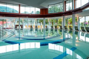 a large pool in a building with glass windows at Vivea Hotel Bad Goisern in Bad Goisern