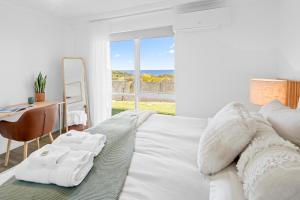 ein Schlafzimmer mit einem Bett mit Schreibtisch und einem Fenster in der Unterkunft Salt & Sky - Luxe Coastal Getaway in Coffs Harbour