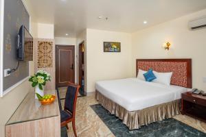 a hotel room with a large bed and a desk at Sea Front Apartment & Spa Da Nang in Danang