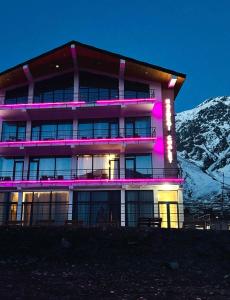 a building with purple lights in front of a mountain at 3100 Boutique Hotel Kazbegi in Stepantsminda