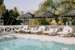een rij stoelen en parasols naast een zwembad bij METT Singapore in Singapore