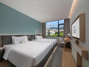 a hotel room with two beds and a flat screen tv at The Liyi Hotel Guangzhou Taikoo Hui Huashi Metro Station Branch in Guangzhou +38 photos