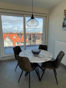 a dining room with a table and chairs and a large window at Zeebries Penthouse in Koksijde +3 photos