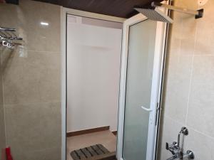 una ducha con puerta de cristal en un baño en Suseelagam, en Sīrkāzhi