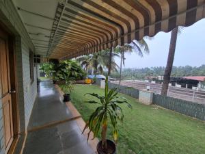 a porch of a house with awning and palm trees at Charu's Villa By Elite Stays in Jāmb