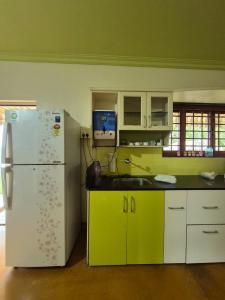 a kitchen with a white refrigerator and green cabinets at Charu's Villa By Elite Stays in Jāmb