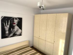 a bedroom with a dresser and a picture of a woman at Old Center Apartment in Craiova