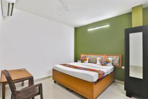 a bedroom with a bed and a table and a mirror at FabHotel Raas Inn in Lucknow