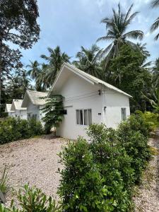 a white house with palm trees in the background at Houses in Ban Nua