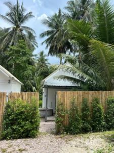 a fence in front of a house with palm trees at Houses in Ban Nua