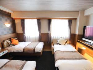 a hotel room with two beds and a flat screen tv at Hotel Areaone Kochi in Kochi