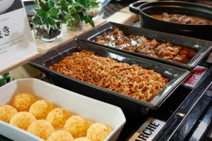a buffet with trays of food on a table at KOKO HOTEL Kobe Sannomiya in Kobe