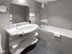 a bathroom with a sink and a tub and a mirror at Aparthotel Adagio Nice Promenade des Anglais in Nice +45 photos