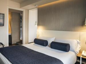 a bedroom with a large white bed with two pillows at Mercure Barcelona Condor in Barcelona