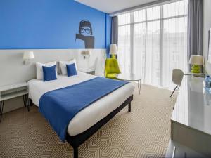 a hotel room with a bed and a blue wall at Ibis Styles Wroclaw Centrum in Wrocław +100 photos
