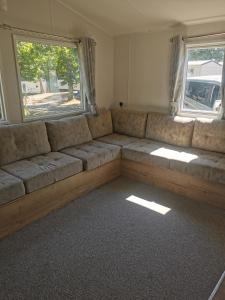 a couch in a living room with two windows at Thornesbay holiday park in Isle of Wight