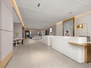 a woman standing behind a counter in a lobby at The Liyi Hotel Guangzhou Taikoo Hui Huashi Metro Station Branch in Guangzhou