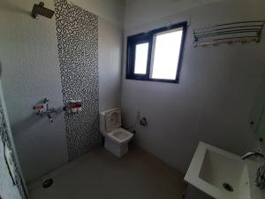 a bathroom with a toilet and a sink and a window at Shukla Bhawan in Panchkula