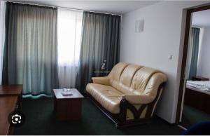 ein Wohnzimmer mit einem Ledersofa in einem Hotelzimmer in der Unterkunft Pensiunea Lac Calinesti 
